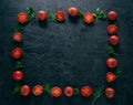 Flat lay of red ripe tomatoes lies in form of frame on dark background with green parsley and dill. Healthy vegeterian dish. Royalty Free Stock Photo