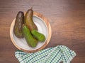 Flat lay of ripe avocados on a white dish on a wooden cutting board with cloth on a wooden table. Royalty Free Stock Photo