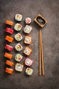 Flat lay rows of sushi rolls, soy sauce and chopsticks on a dark rustic background. View from above. Traditional asian food Royalty Free Stock Photo