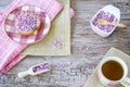 Flat lay with rusk, sweet pink purple sprinkles and cup of tea. Against wooden background