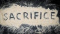 Flat lay of SACRIFICE word written on white sand Royalty Free Stock Photo