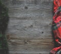 Flat lay of scarf with Christmas tartan texture and branch of tree on wooden background with space in middle - Christmas or New