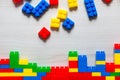 Flat lay and scattered multi coloured toy blocks on white wooden palette.