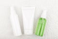 Set of cosmetic bottles for face washing, exfoliating and moisturizing on white flossy towel