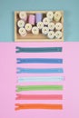 Flat lay of sewing material contains the zipper and colorful thread rolls for sewing on two tone background, Sewing and Royalty Free Stock Photo