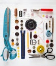 Flat lay of sewing tool and accessories on white wooden background