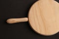 Flat lay shot of a chopping board with a handle on a black surface