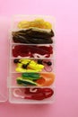 Flat lay shot of different fishing lures in a plastic box on a pink surface Royalty Free Stock Photo