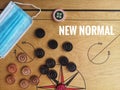 Flat lay shot a image word - NEW NORMAL and face mask/striker/carrom mens ball on carrom board with selective focus.