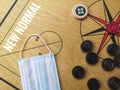Flat lay shot a image word - NEW NORMAL and face mask/striker/carrom mens ball on carrom board with selective focus.