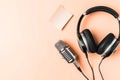 Flat lay shot of professional headphones and a radio microphone isolated on a light peach background. Podcast and radio concept