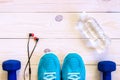 Flat lay shot of Sport equipment, shoes, water, earphone on wooden background.