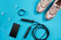 Flat lay shot of Sport equipment. Sneakers, jump rope, earphones and phone on blue background. Royalty Free Stock Photo