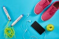 Flat lay shot of Sport equipment. Sneakers, jump rope, earphones and phone on blue background. Royalty Free Stock Photo