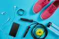 Flat lay shot of Sport equipment. Sneakers, jump rope, earphones and phone on blue background. Royalty Free Stock Photo