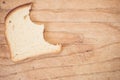 Flat lay of a slice of bitten white bread on a wooden table with space for your text