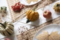 flat lay of small pumpkins and dry brown maple leafs on white plates