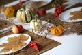 Flat lay of small pumpkins and dry brown maple leafs on white plates