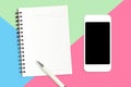 Flat lay of Smartphone, blank notebook and white pen on pastel color blue, green, pink paper background Royalty Free Stock Photo