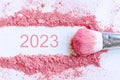 Flat lay of smear of crushed pink cosmetics with 2023 number, copy space, top view. New year concept