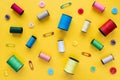 Spools of colored thread, buttons and safety pins on yellow background Royalty Free Stock Photo