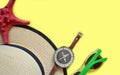 Flat lay with straw hat, sunglasses, compass and starfish on yellow pastel background. T