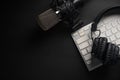 Flat lay, Studio microphone with professional headphones on a PC keyboard. Black on a black background. Podcasts, radio, streams, Royalty Free Stock Photo