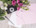Flat lay style with camera, roses, notebook, earphones and pen
