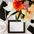 Flat lay styled framed composition with blank frame, sunglasses, saturated bouquet, black leather notebook and parfume