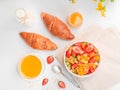 Flat lay summer breakfast with bowl of healthy fresh fruit salad, cup of tea and croissants on white background Royalty Free Stock Photo