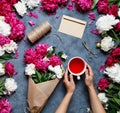 Flat lay summer flower background. A bouquet of flowers of peonies, the hands of women and keep a cup of karkade tea