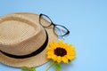 Flat lay with sunglasses, straw boater hat and bright big yellow sunflower on blue background. Travel summer concept. Copy space Royalty Free Stock Photo