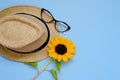 Flat lay with sunglasses, straw boater hat and bright big yellow sunflower on blue background. Travel summer concept. Copy space Royalty Free Stock Photo