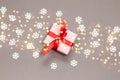 Flat lay of surprise gift box, red ribbon, glitter star confetti and snow on grey background with copy space. Christmas, New Year Royalty Free Stock Photo