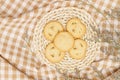 Flat lay of sweets, Danish butter cookie on rattan plate and flower over brown gingham cloth