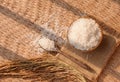 Flat lay of Thai Jasmine rice in ceramic bowl with wooden spoon and ear of paddy in threshing bamboo basket, top view Royalty Free Stock Photo