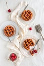 Flat lay of three cherry pies and fresh cherries on white plates  a white background and a serving utensil Royalty Free Stock Photo