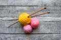 Three colored wool balls, knitting needles on the wooden background Royalty Free Stock Photo