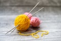 Three colored wool balls, knitting needles on the wooden background Royalty Free Stock Photo