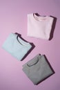 Flat lay of three folded pastel sweatshirts isolated on pale purple background Royalty Free Stock Photo
