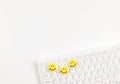 flat lay of three yellow circle smiling faces on white computer keyboard on white background Royalty Free Stock Photo