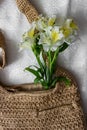 Flat lay top view bamboo woman bag and spring flowers on white cloth background