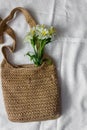 Flat lay top view bamboo woman bag and spring flowers on white cloth background