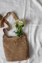 Flat lay top view bamboo woman bag and spring flowers on white cloth background