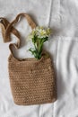 Flat lay top view bamboo woman bag and spring flowers on white cloth background