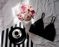 Flat lay. Top view black lace lingerie. Beauty blog concept. Bouquet of roses and pions, coffee on white bed background Royalty Free Stock Photo