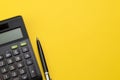 Flat lay or top view of black pen with calculator on vivid yellow background table with blank copy space, math, cost, tax or