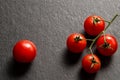 Flat lay, top view. Close up, macro. A sprig of juicy cherry tomatoes. Nearby is one red tomato. Black background. Copy space Royalty Free Stock Photo