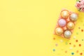 Flat lay top view colorful easter egg painted in pastel colors composition and spring flowers on yellow pastel color background. Royalty Free Stock Photo