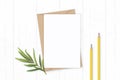 Flat lay top view elegant white composition letter kraft paper envelope yellow pencils and tarragon leaf on wooden background